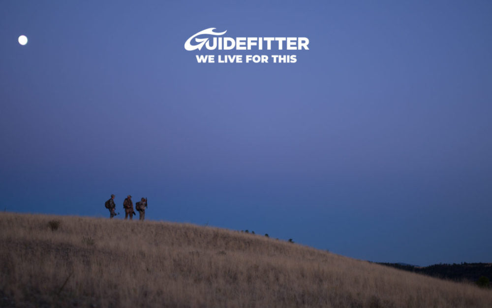 Group of hunters walking along a hill below the Guidefitters logo for the Best Guided Hunting And Fishing Adventures