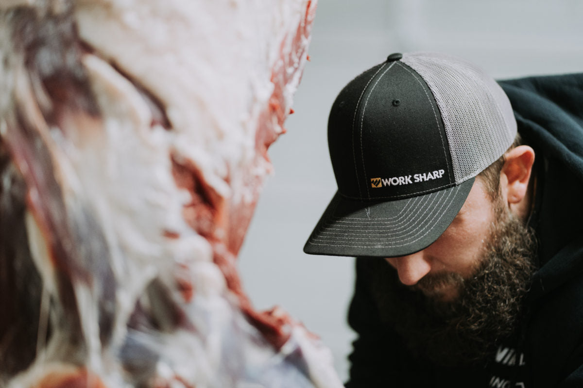 Man wearing a Work Sharp hat is busy rendering the remains of his hunt