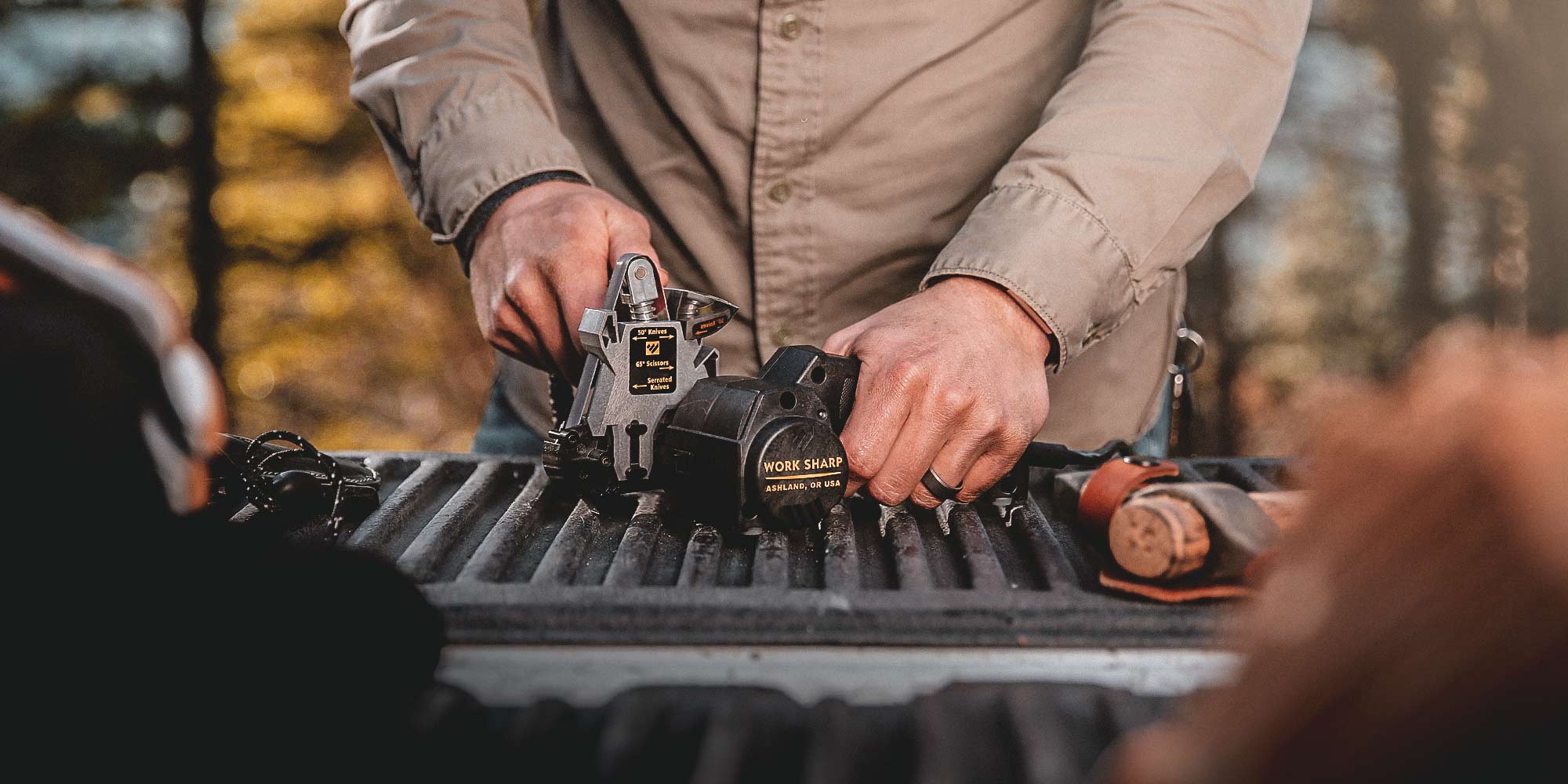 Man sharpening a pocket knife in the Work Sharp Knife and Tool Sharpener on the back of a tale gate
